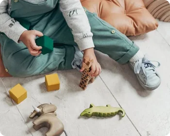 Kind spielt mit farbigen bauxili Tierfiguren